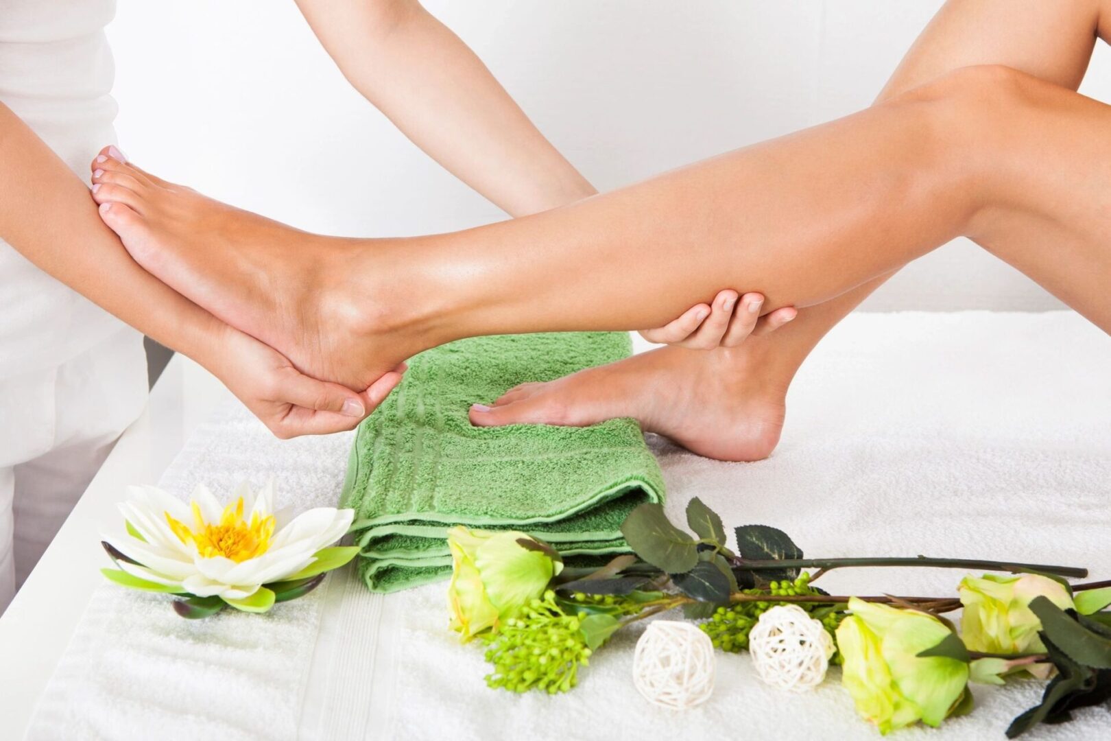A relaxing foot massage in a spa setting with flowers and towels.