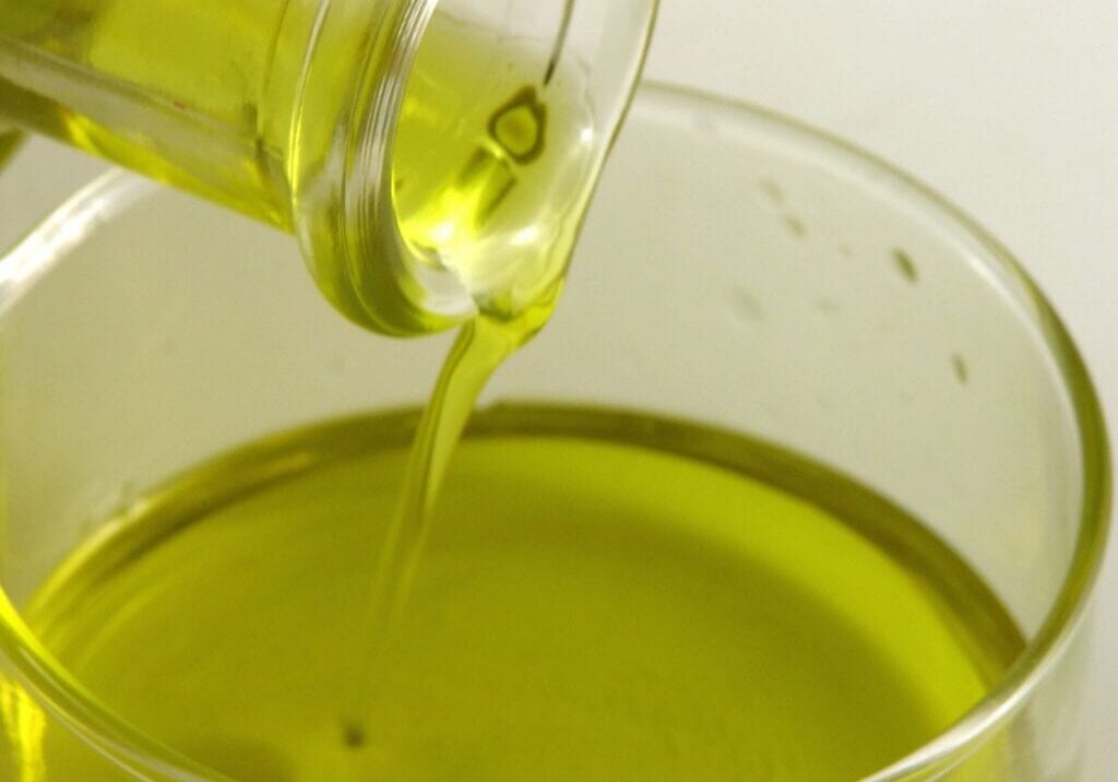 Olive oil being poured into a glass bowl.